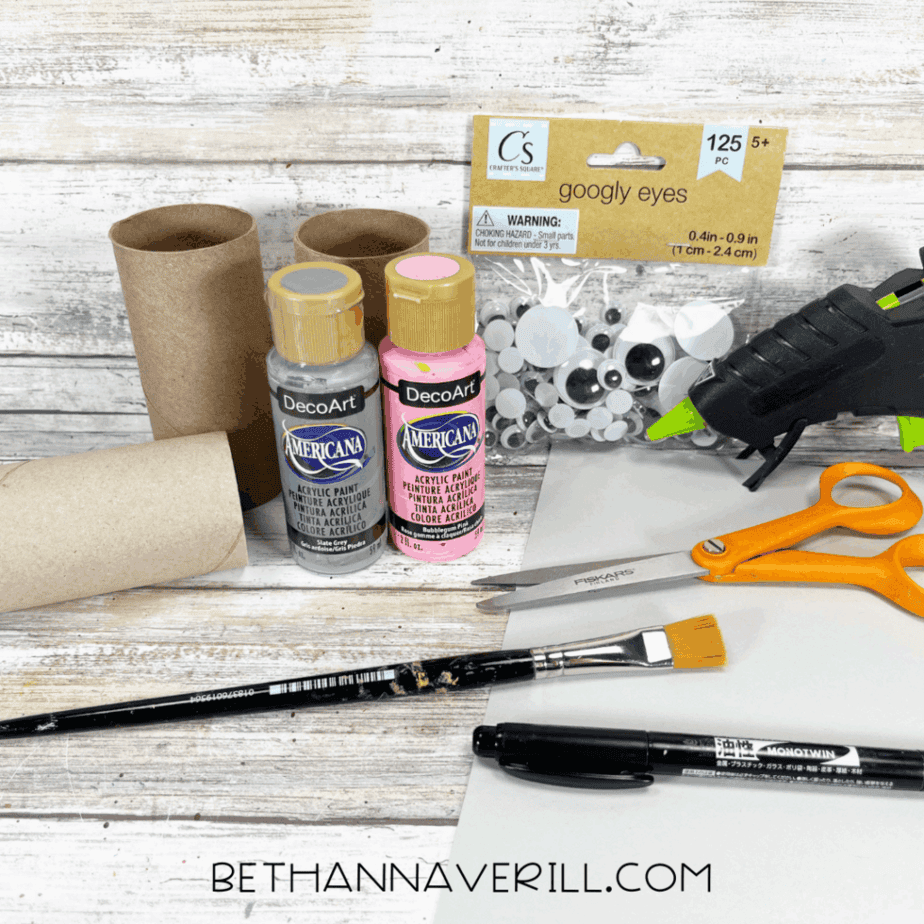 Materials for elephant paper roll craft including paint, googly eyes, scissors, glue, and toilet paper rolls.