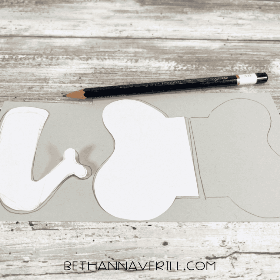 Pencil tracing elephant ear and trunk templates on gray paper.