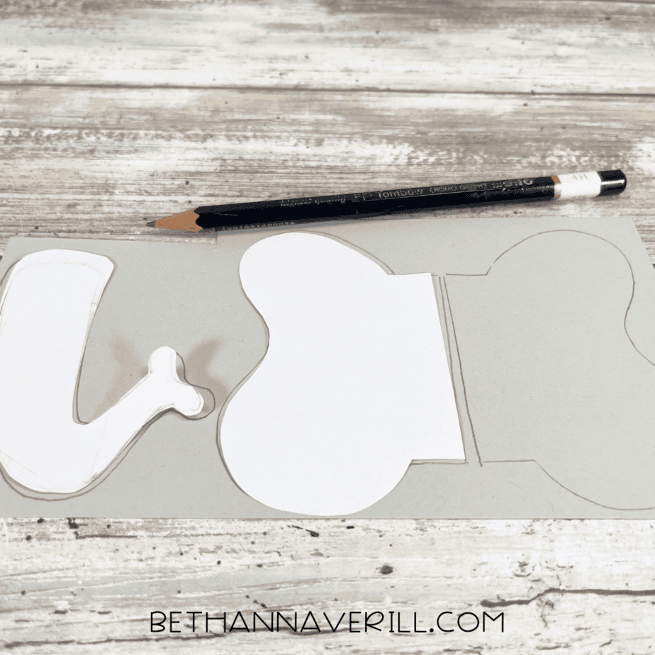 Pencil tracing elephant ear and trunk templates on gray paper.