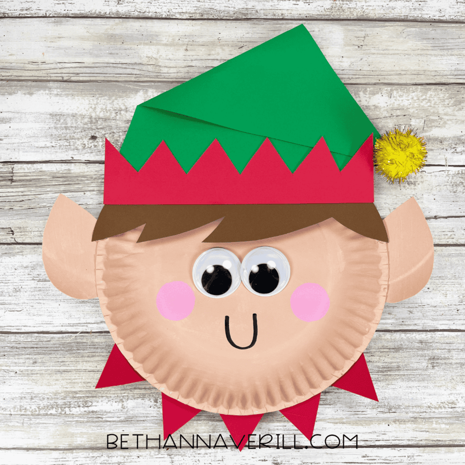 Finished Elf Boy paper plate craft with pom-pom hat topper and smiling face.