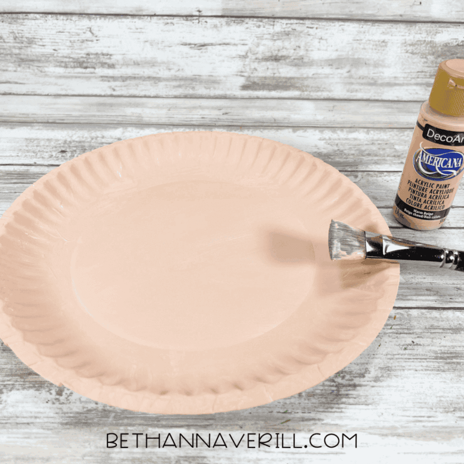 Paper plate painted with skin-tone acrylic paint.