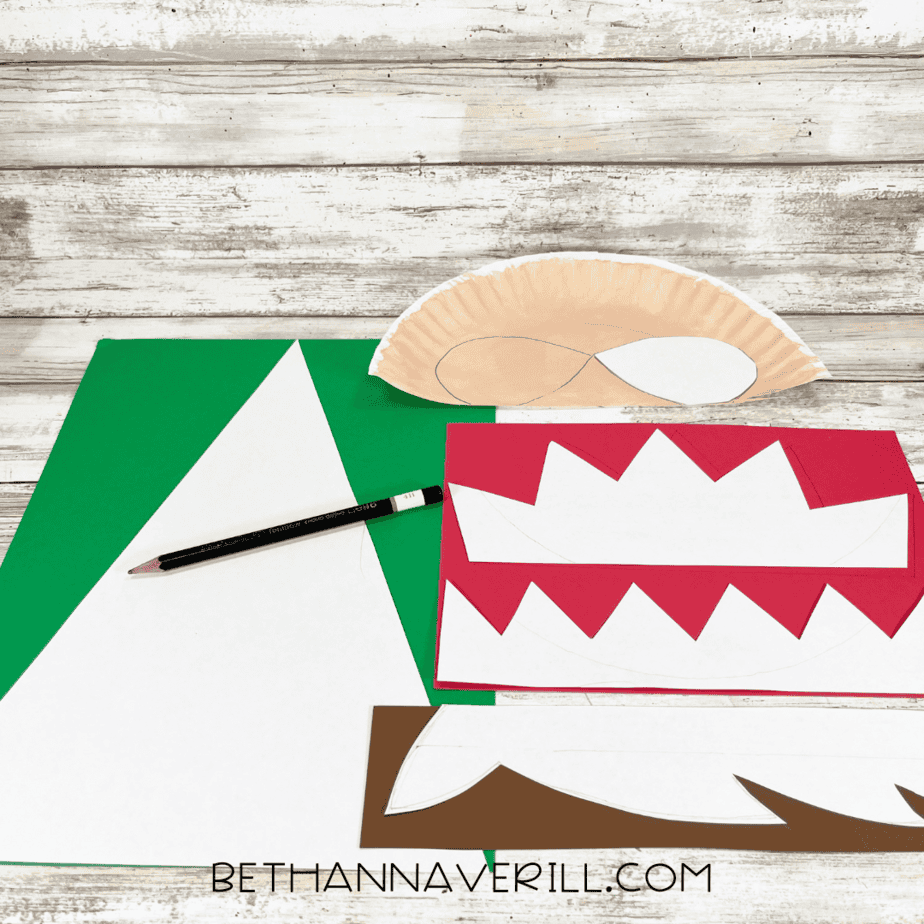 Green, red, and brown construction paper with elf hat, hair, and trim patterns drawn on.
