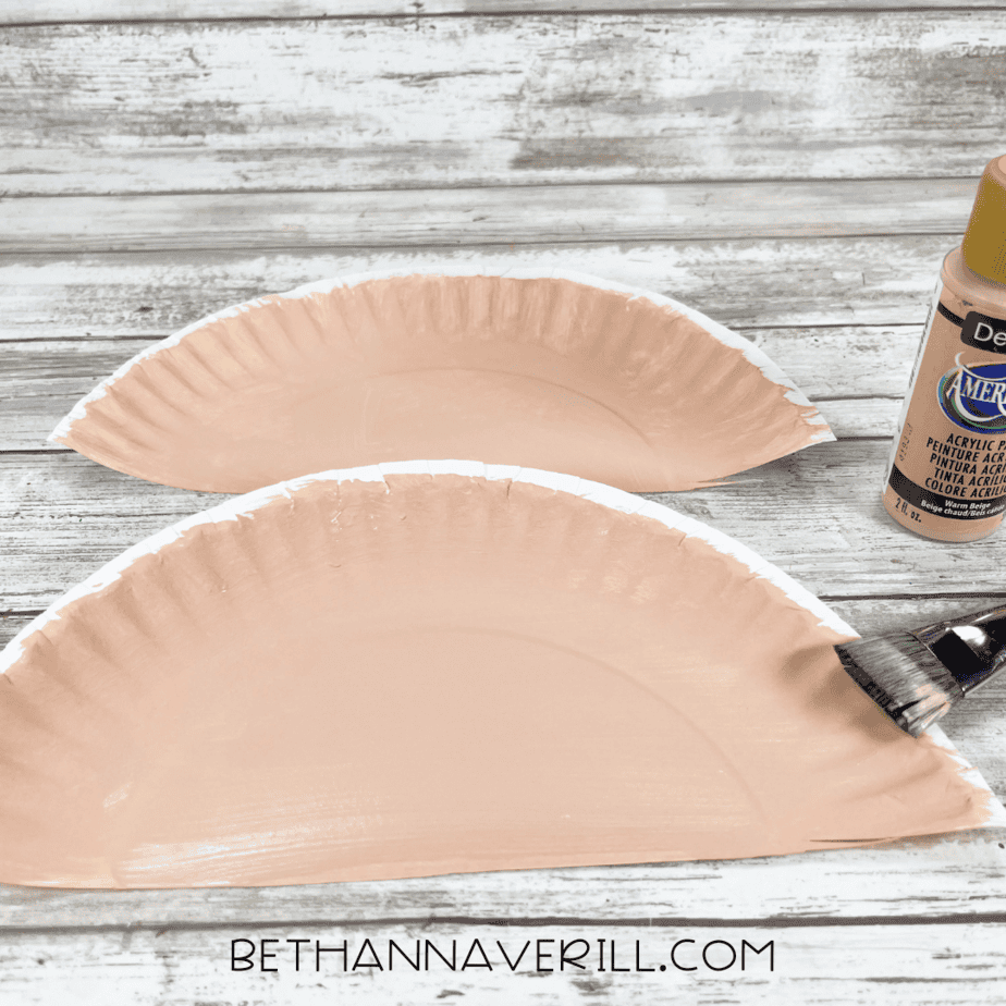 Two half paper plates painted and ready to use as ears.