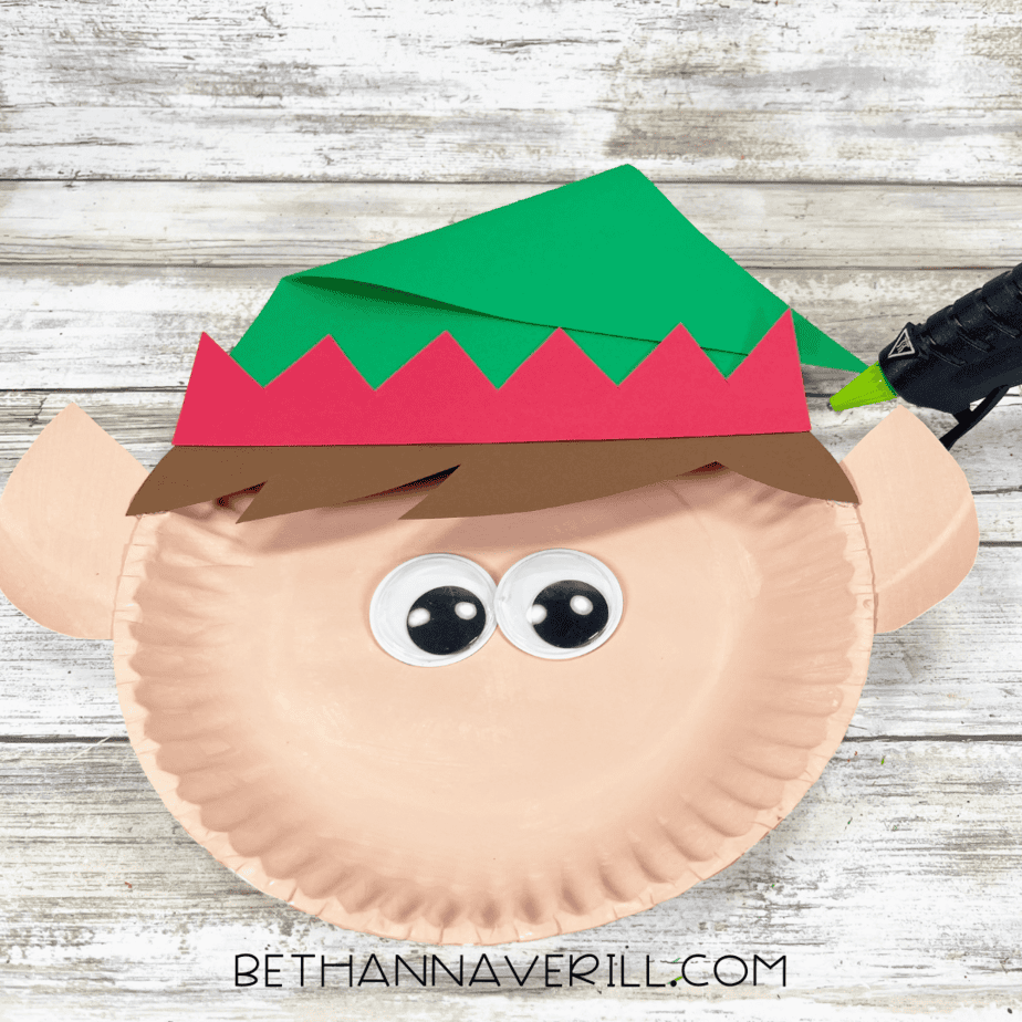 Elf face with googly eyes, hat, hair, and ears glued in place.
