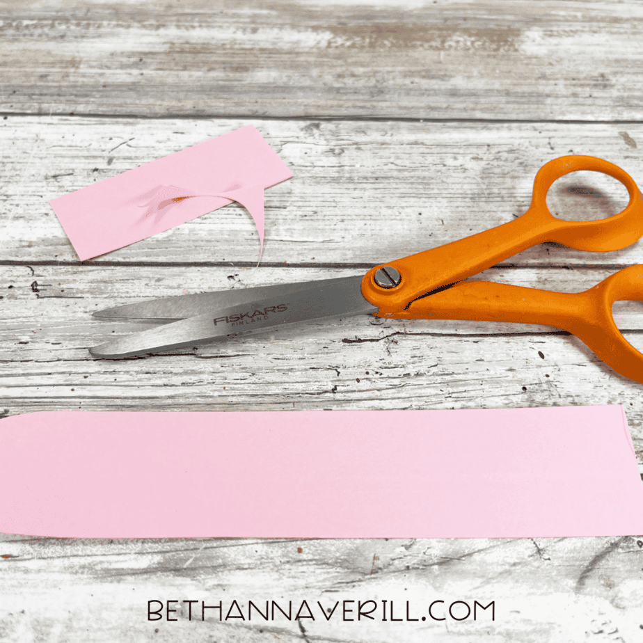 A strip of pink construction paper cut out and trimmed with scissors.