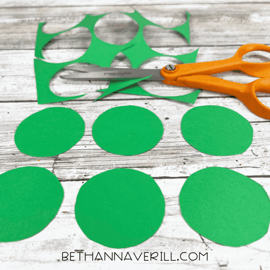 Several small and medium green circles cut out and spread on the table.