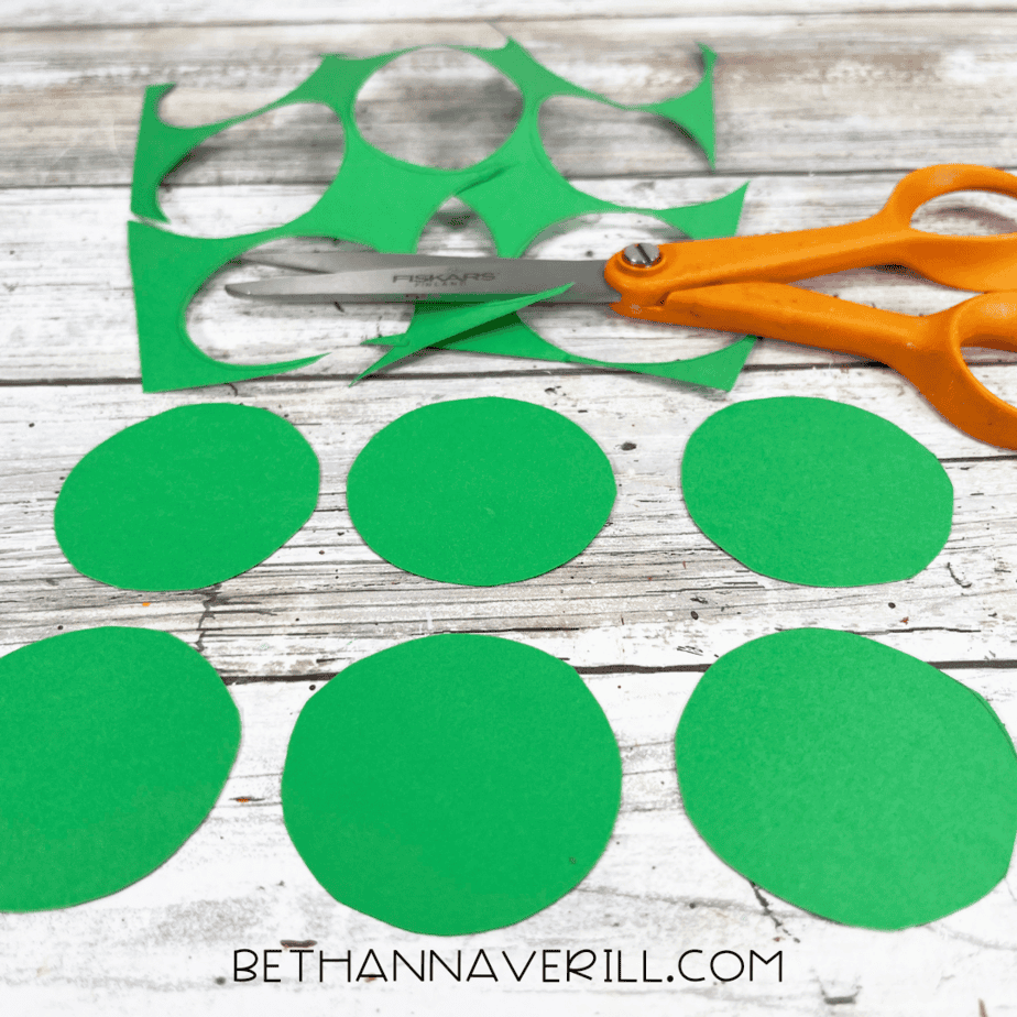 Several small and medium green circles cut out and spread on the table.