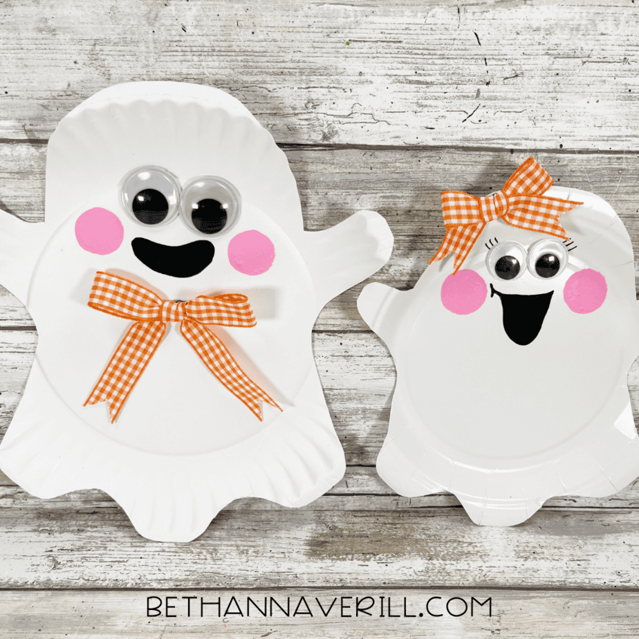 Finished paper plate ghosts with googly eyes, rosy cheeks, black smiles, and orange bows.