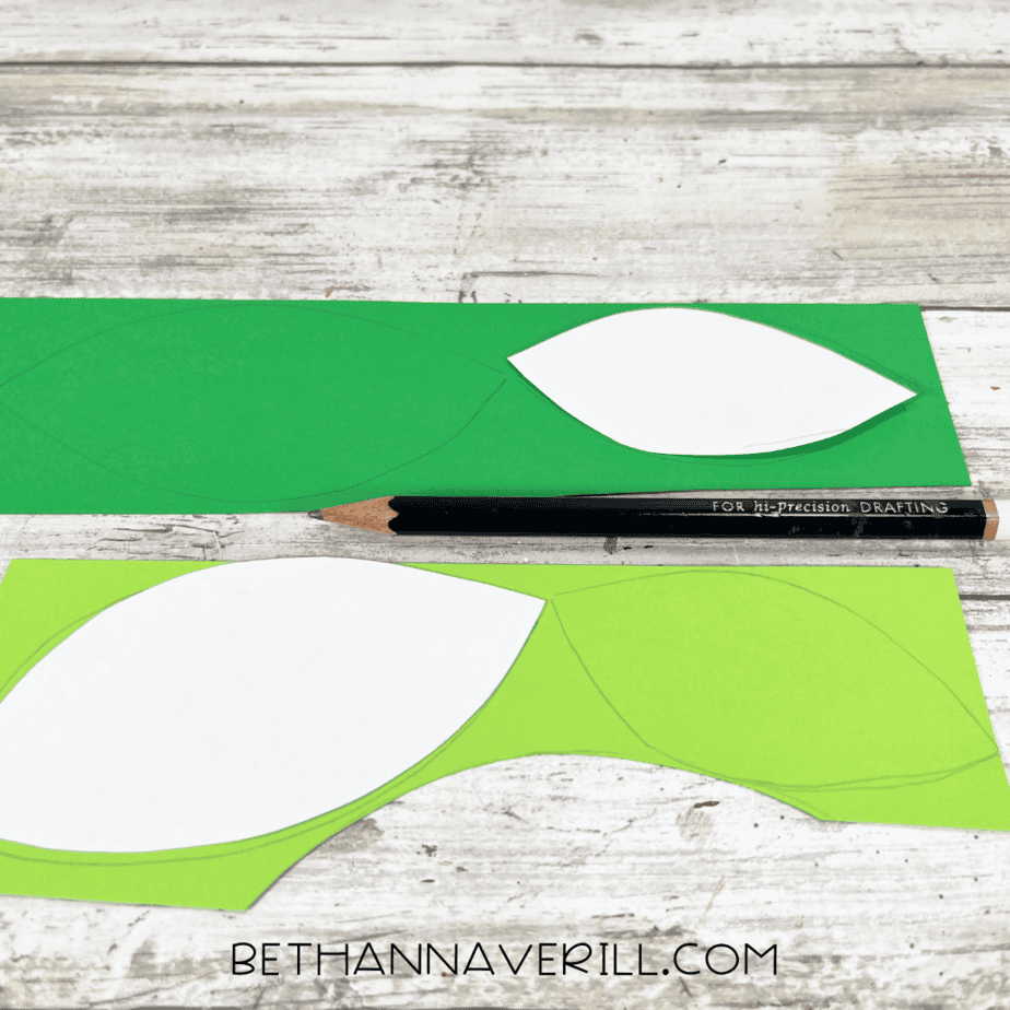 Green construction paper with leaf templates traced on it.
