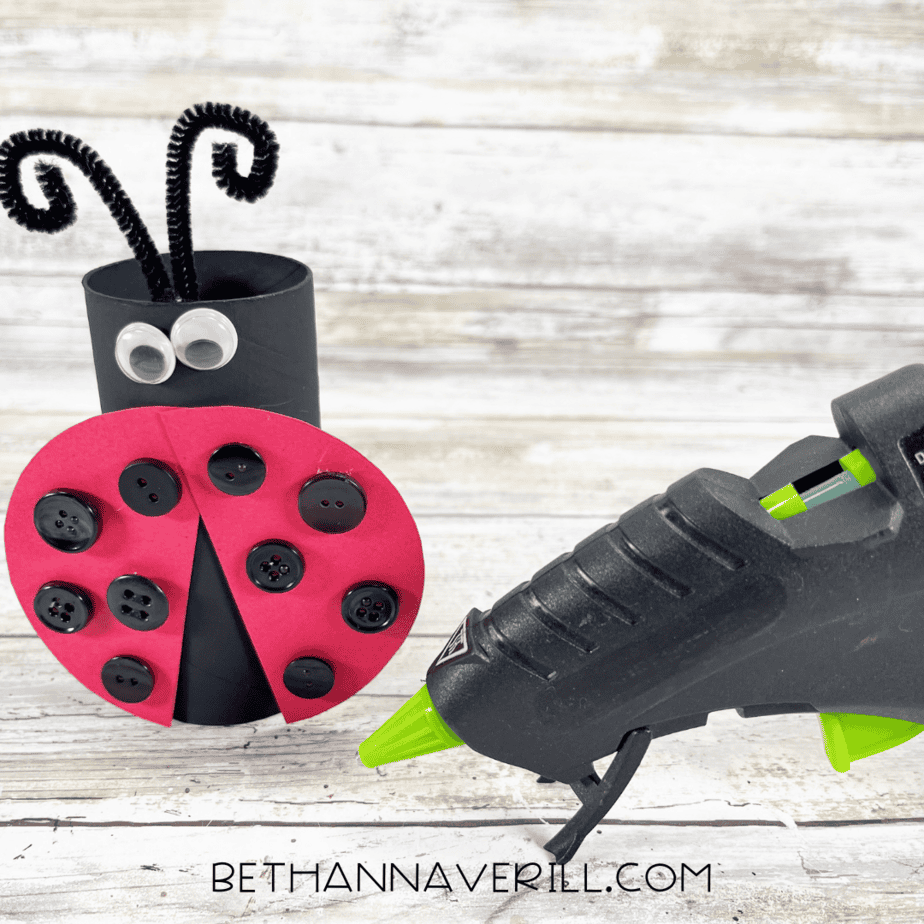 Ladybug paper roll craft with googly eyes, red button-covered wings, and antennae.