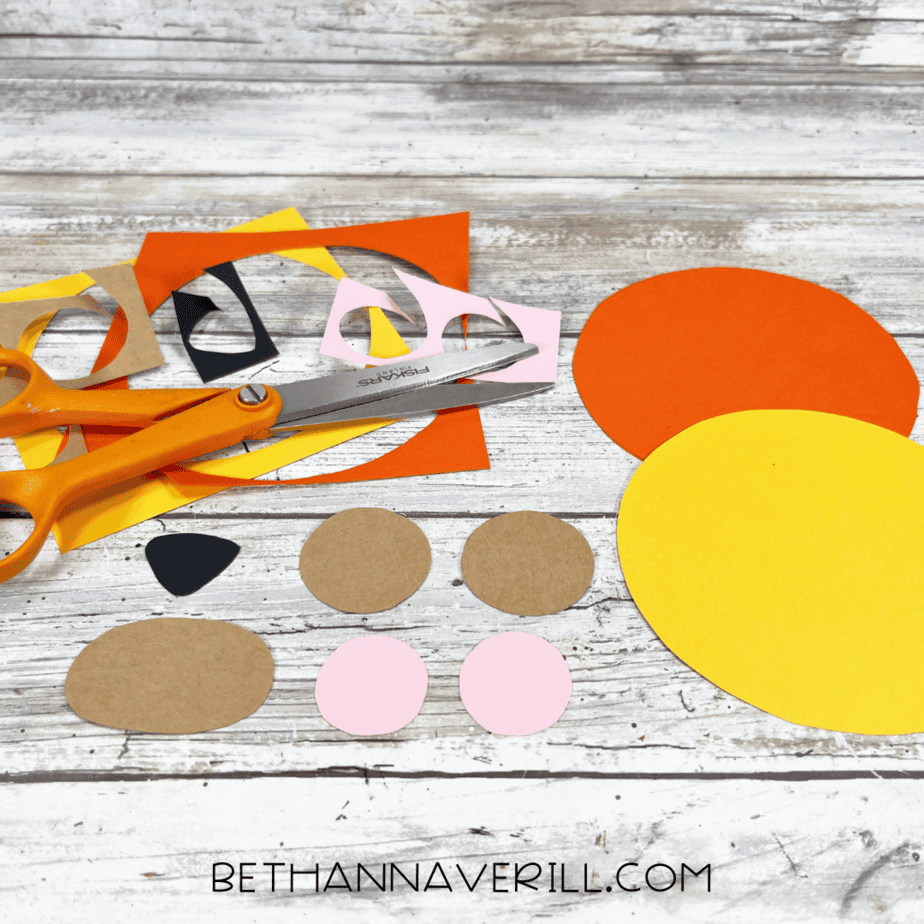 Cut out shapes of mane, ears, and face pieces for lion paper roll craft.