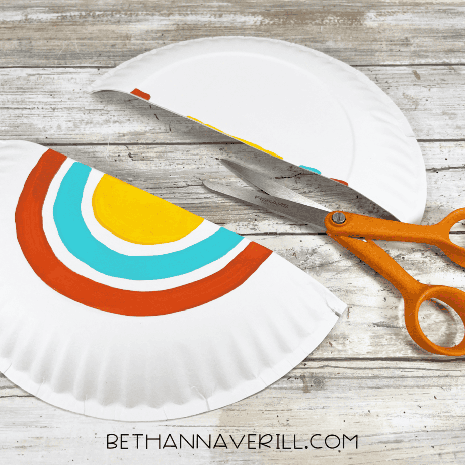 The painted paper plate cut in half with scissors placed on the table.