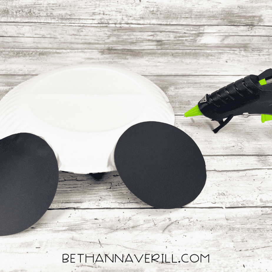 Two black circles glued to paper plate as Mickey Mouse ears.