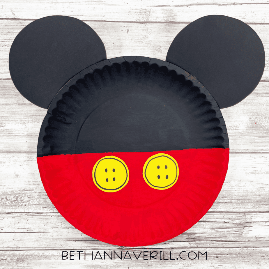 Finished Mickey Mouse paper plate craft with red bottom, black top, ears, and yellow buttons.
