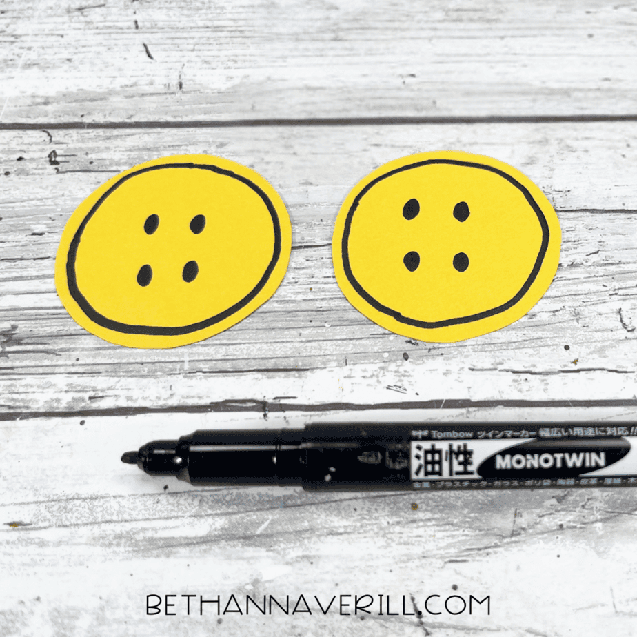 Yellow paper circles with black button details drawn on.