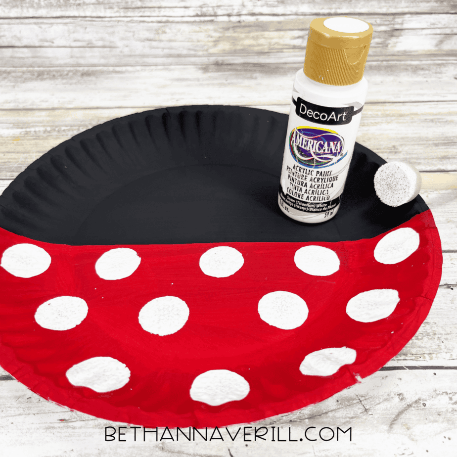 Paper plate with red and black paint, decorated with white polka dots.