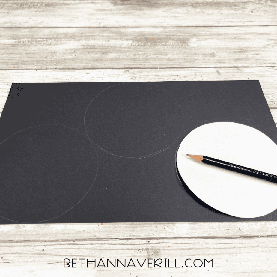 Black construction paper with circles traced on using a pencil.
