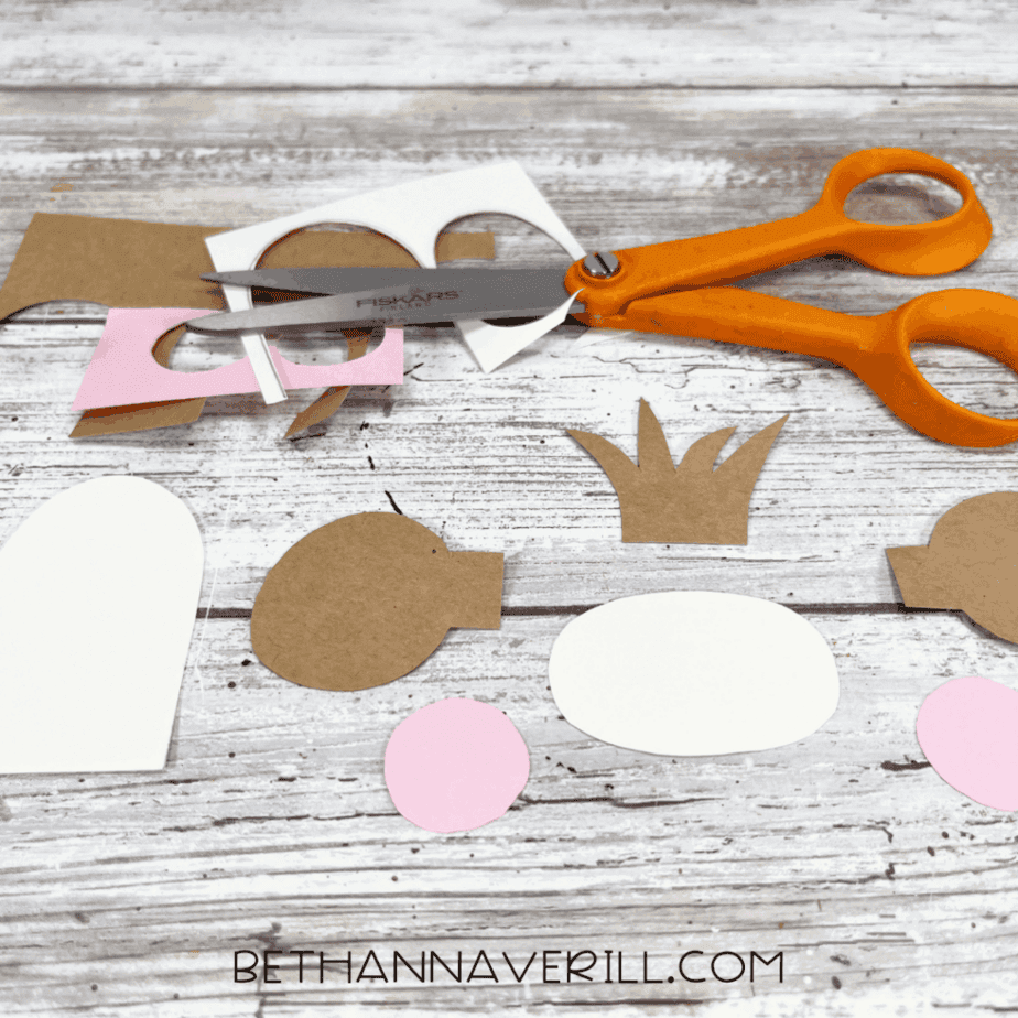 Monkey craft pieces cut out from construction paper, including ears, face, tummy, and hair tuft.