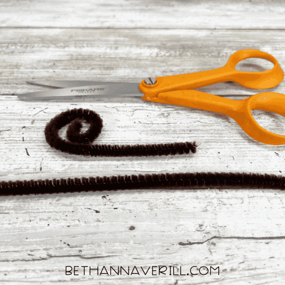 Brown pipe cleaner being curled into a spiral shape for the monkey’s tail.