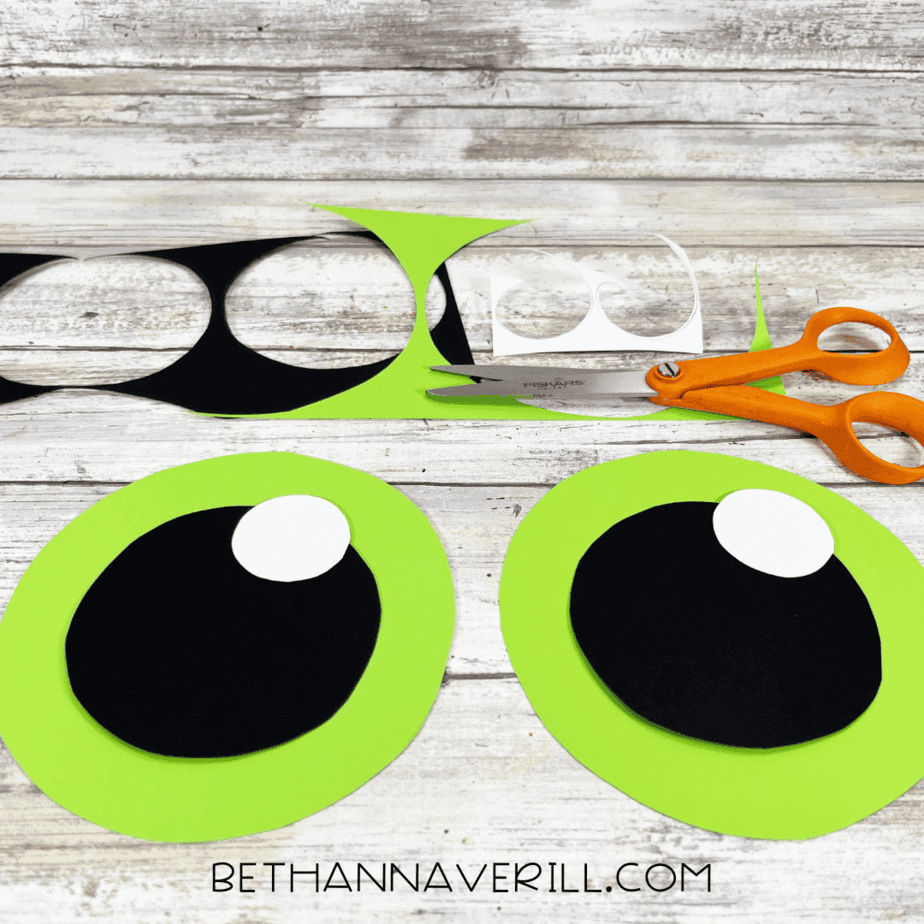 Cut out circles of different sizes in green, black, and white to form the monster’s eye.