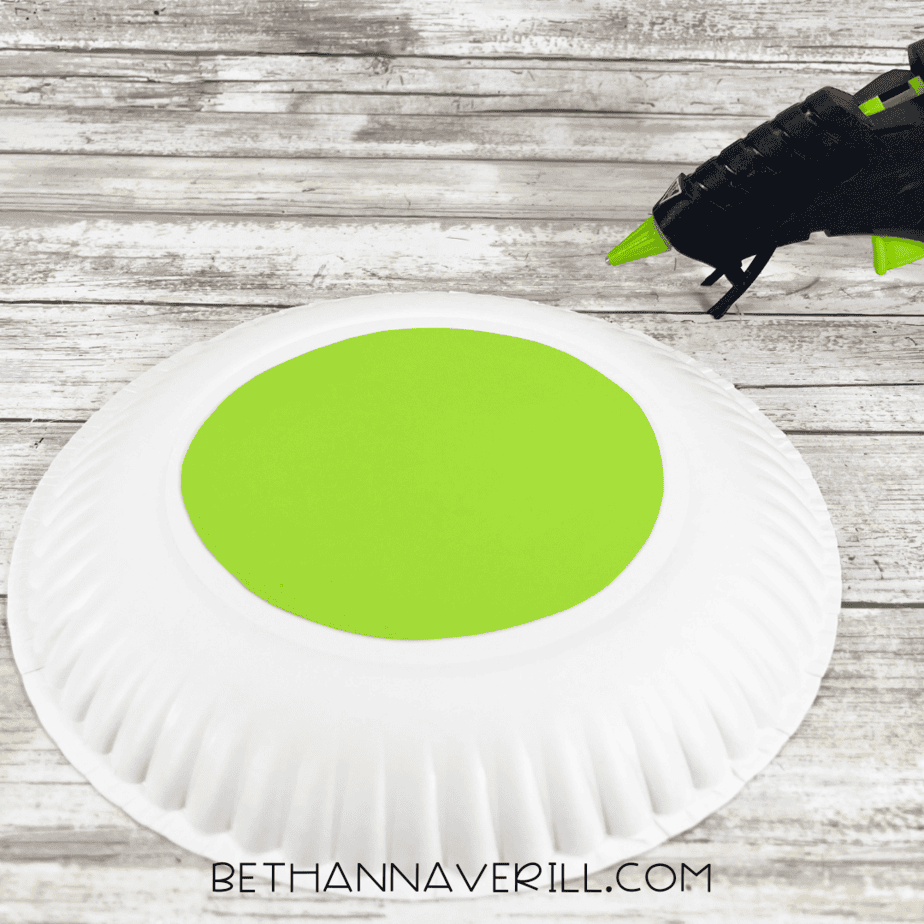 Green circle glued to the center of a white paper plate to begin forming the monster eye.