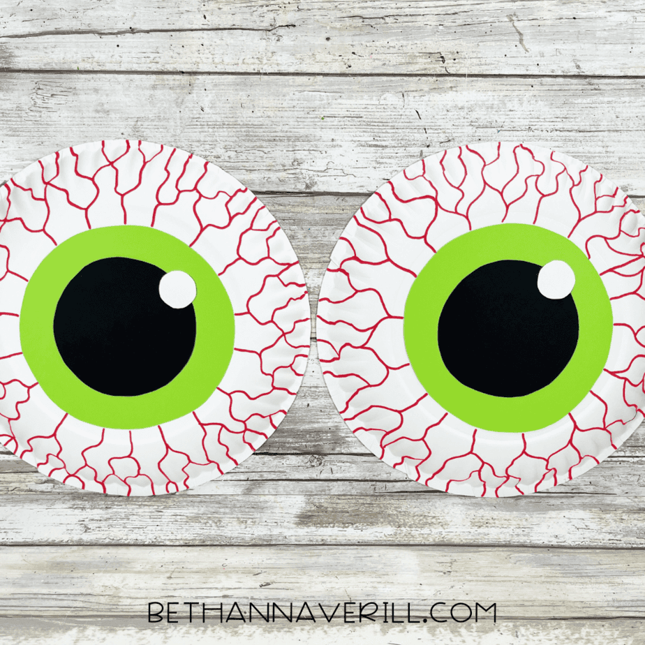 Finished monster eyes paper plate craft with green iris, black pupil, white highlight, and red veins.