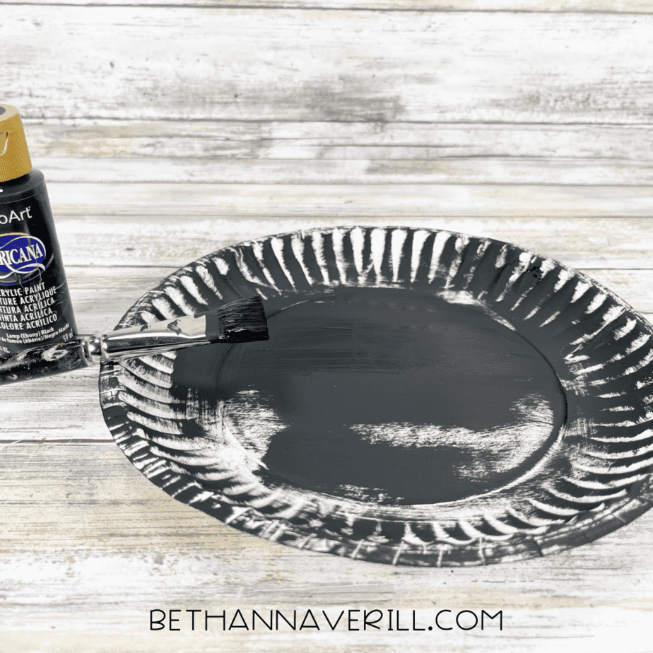 Paper plate painted black with a paintbrush and acrylic paint.