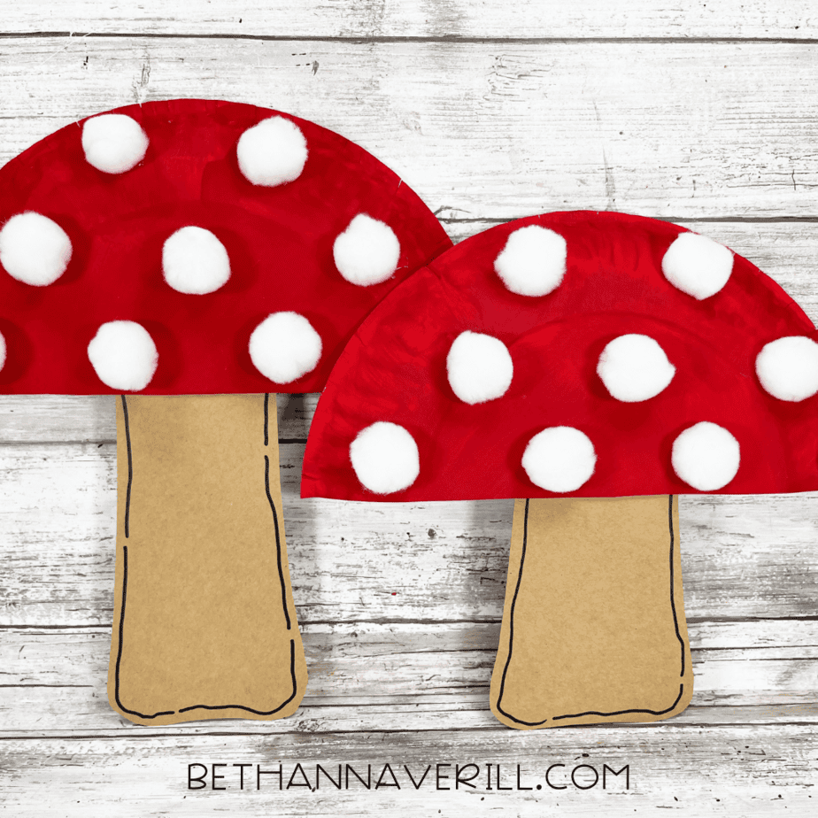 Two finished mushroom paper plate crafts with red caps and white cotton ball spots.