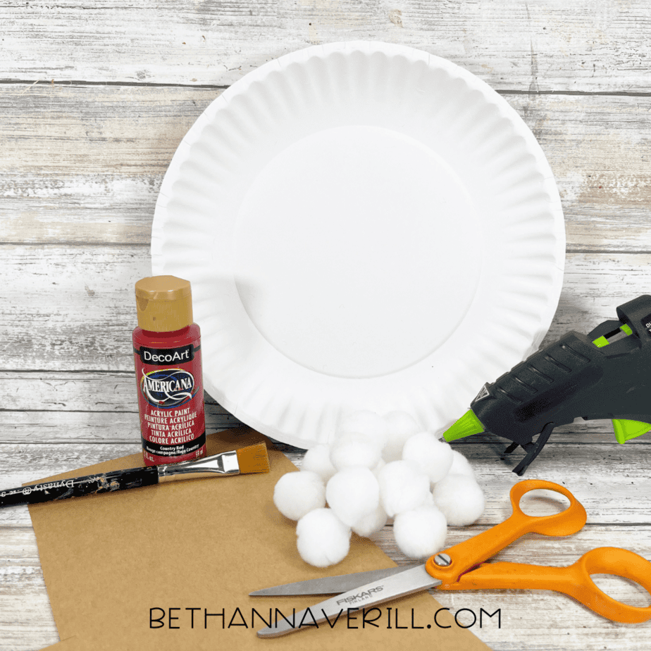 Mushroom paper plate craft supplies including paper plate, red paint, cotton balls, and scissors.