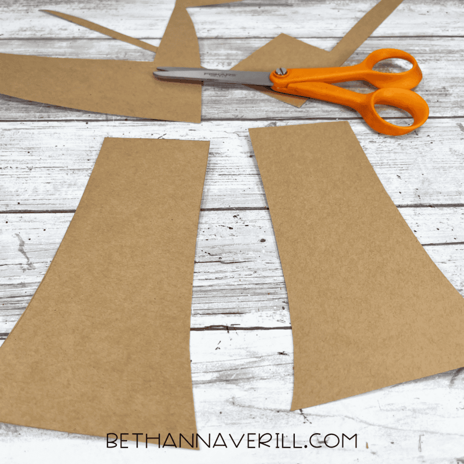 Brown cardstock cut into two mushroom stems with scissors beside them.