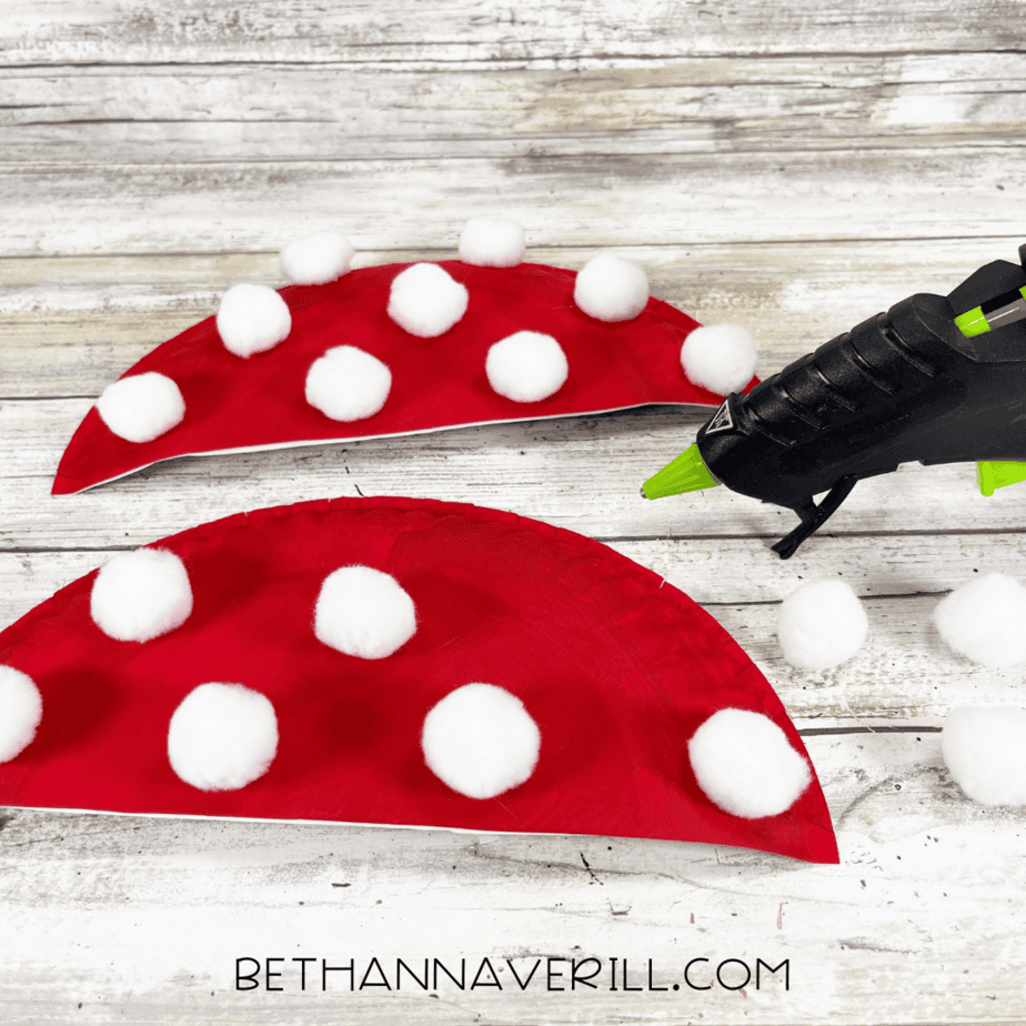 Red paper plate halves decorated with white cotton ball spots.