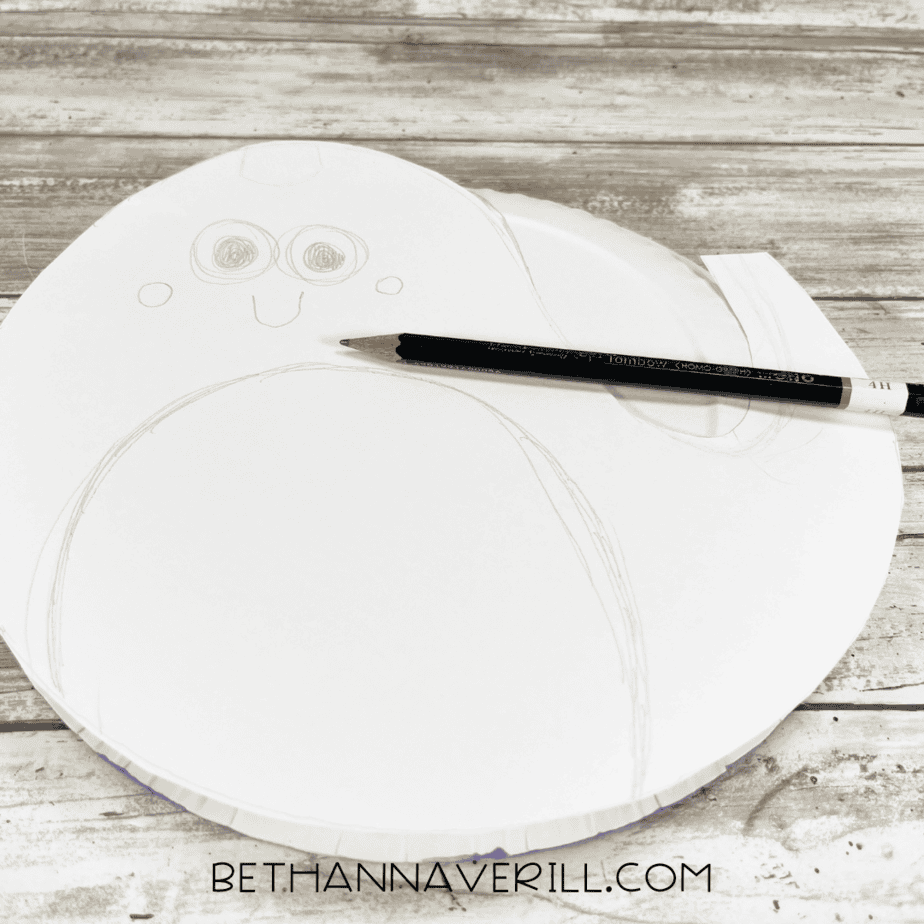 Narwhal outline sketched onto paper plate with pencil.