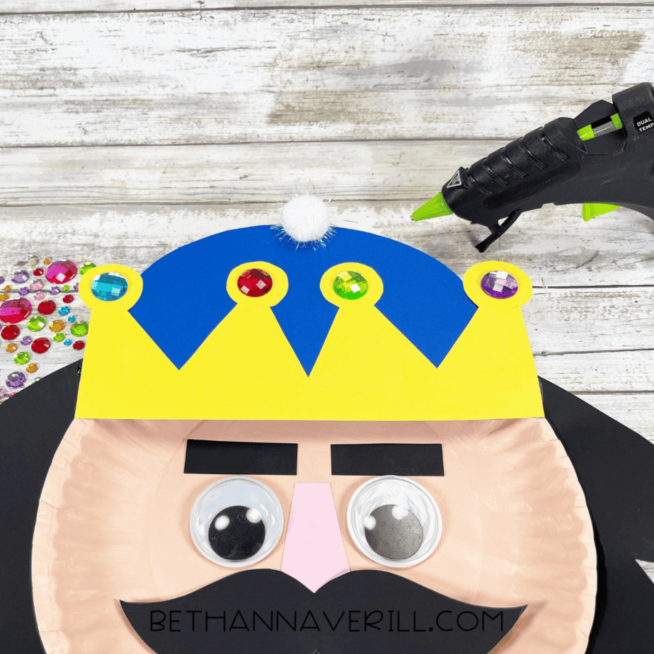 Nutcracker paper plate craft with pompom glued on top of crown.