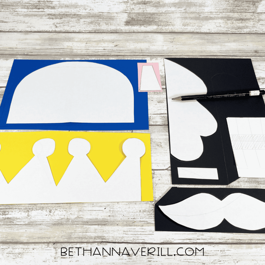 Nutcracker templates traced onto yellow, blue, pink, and black construction paper with pencil.