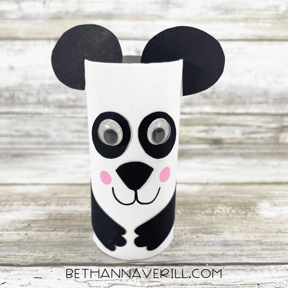 Completed panda paper roll craft with googly eyes, black arms, and pink cheeks.