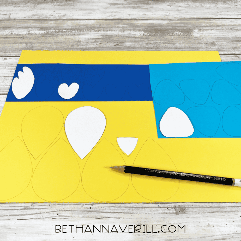 Feather shapes traced onto yellow, blue, and light blue construction paper.