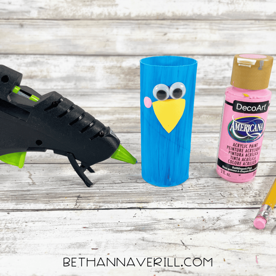 Toilet paper roll with googly eyes, yellow beak, and pink cheeks added.