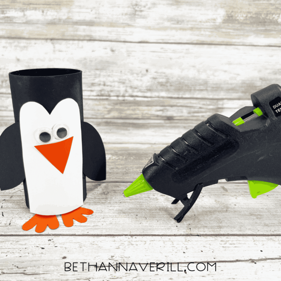 Penguin with glued-on wings and feet next to glue gun.