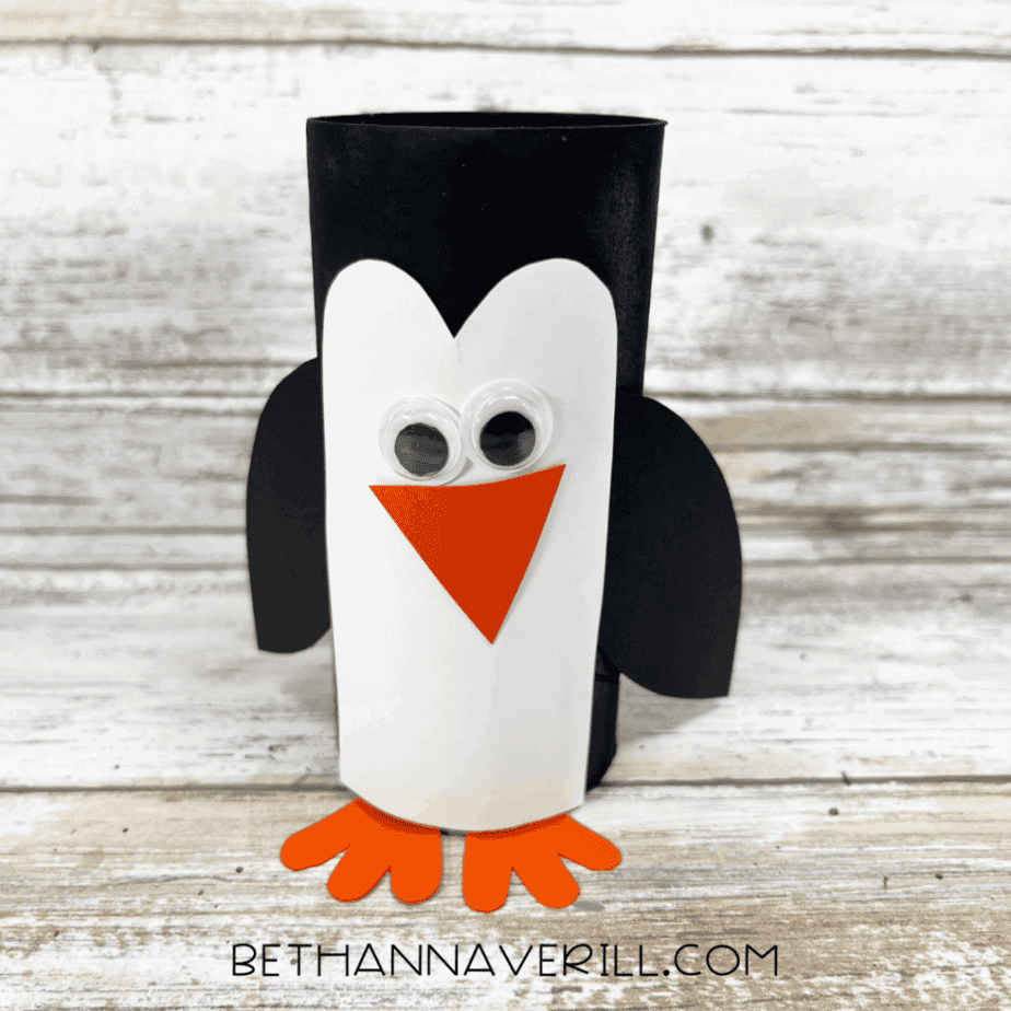 Completed penguin paper roll craft with wings, beak, feet, and eyes.