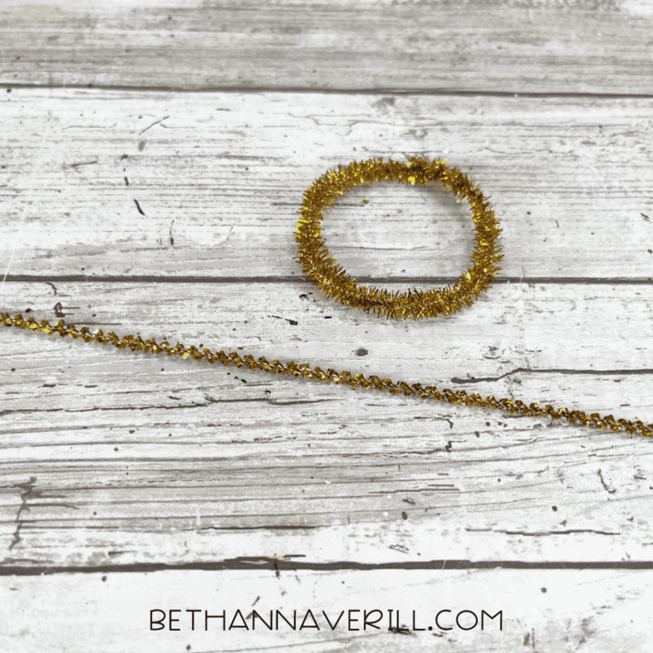 Gold pipe cleaner shaped into an earring.