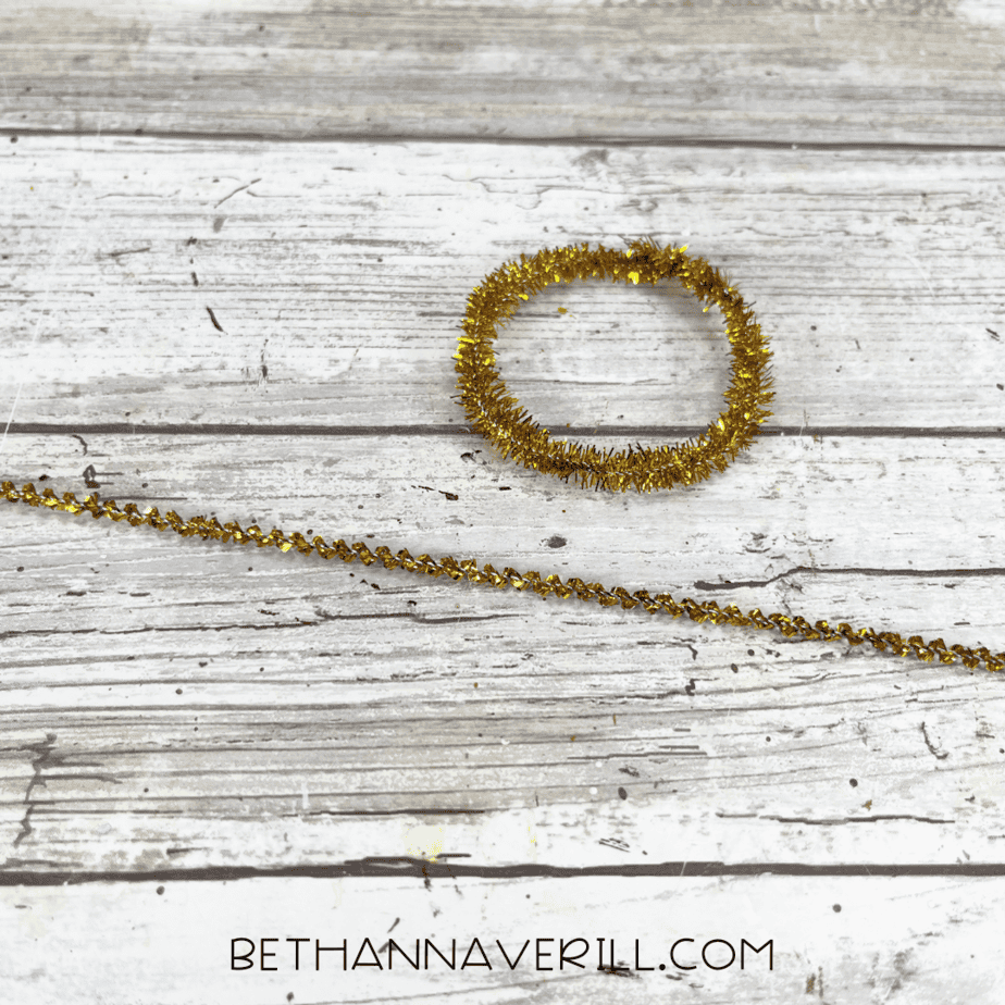 Gold pipe cleaner shaped into an earring.