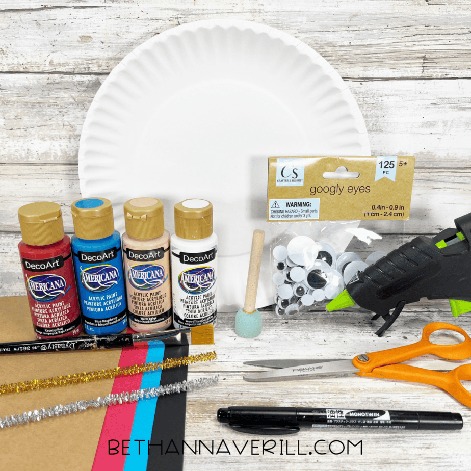 Craft supplies for pirate boy paper plate craft including paint, paper, googly eyes, and pipe cleaners.