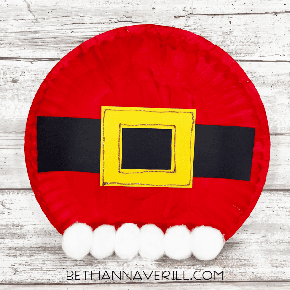 Finished Santa Belt Paper Plate Craft with red plate, black belt, yellow buckle, and cotton trim.