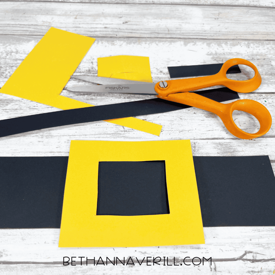 Cut-out yellow buckle and black belt strip with scissors.