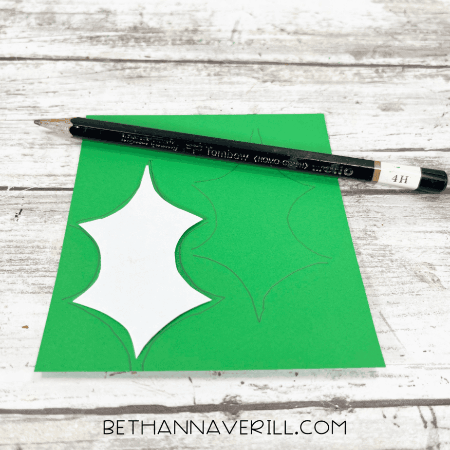 Holly leaf template traced onto green construction paper with a pencil.