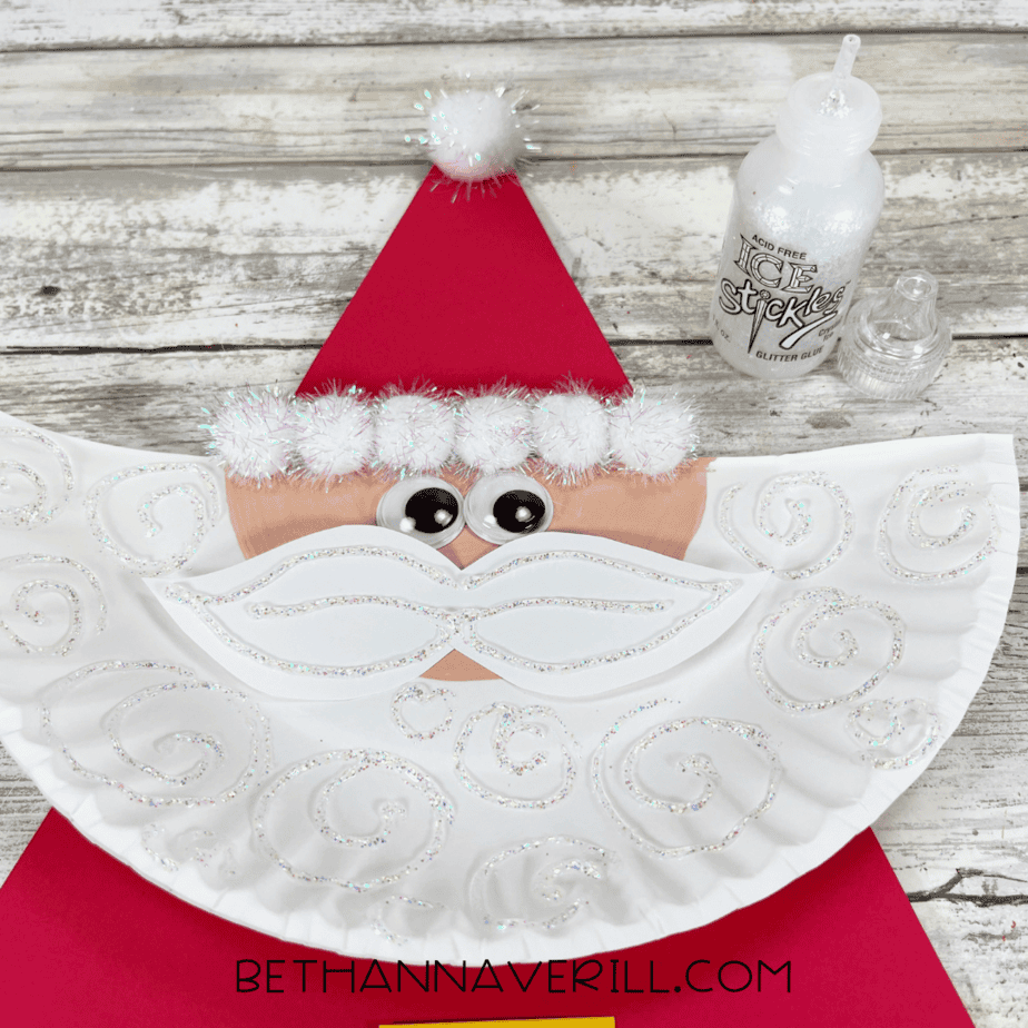 White beard swirled with glitter glue for decoration on Santa paper plate craft.