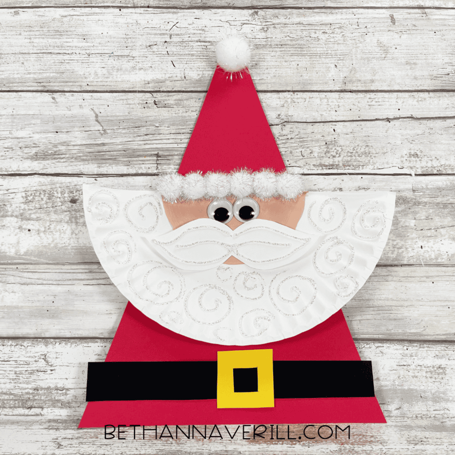 Finished Santa paper plate craft with red hat, cotton ball trim, googly eyes, mustache, and glittery beard.