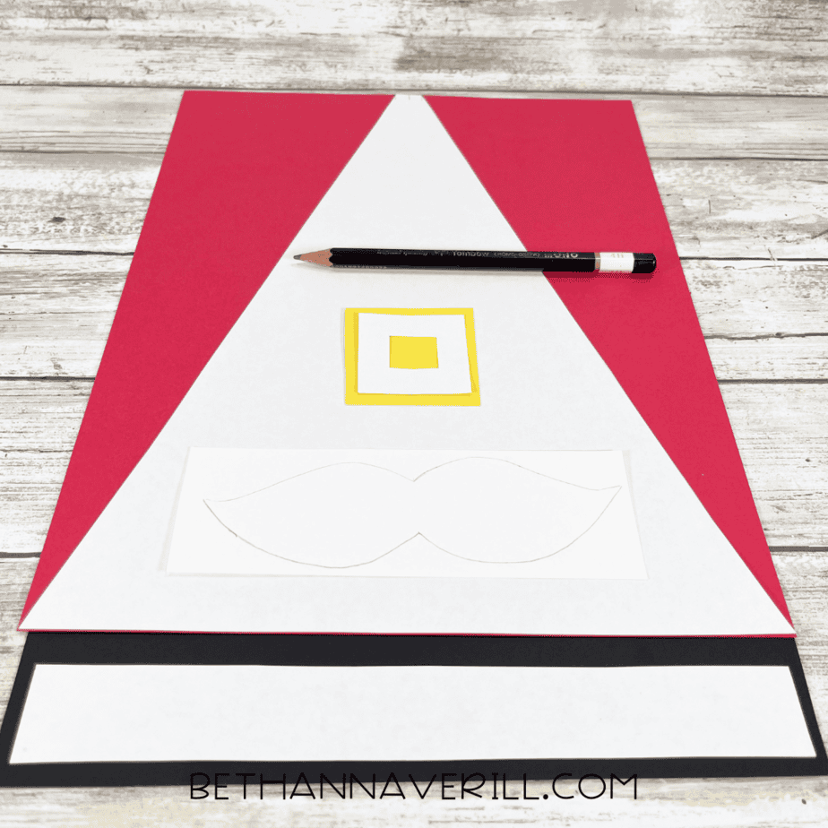 Red triangle, yellow buckle, black strip, and white mustache cut out from construction paper.