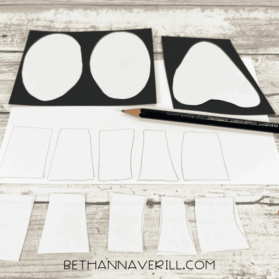Tracing skull face shapes onto black and white construction paper with a pencil.
