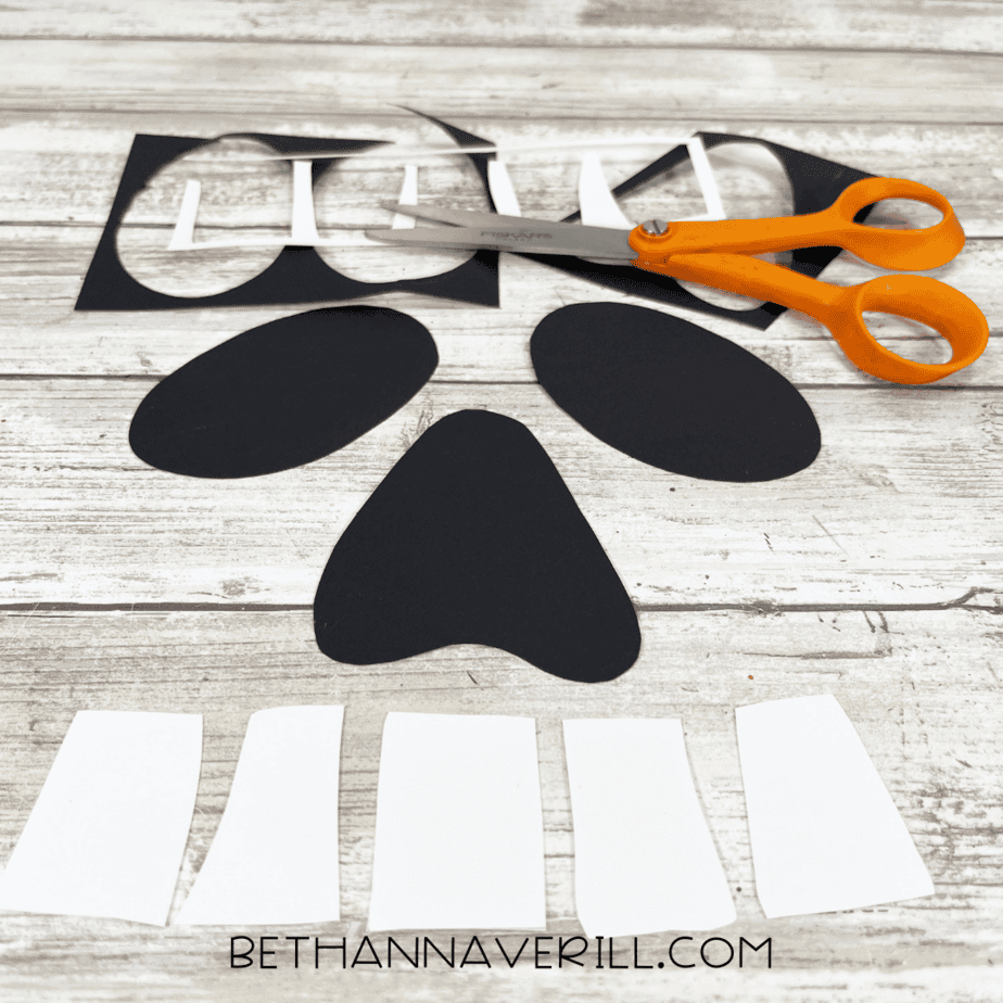 Cut-out black ovals and nose shape with white rectangle teeth pieces.